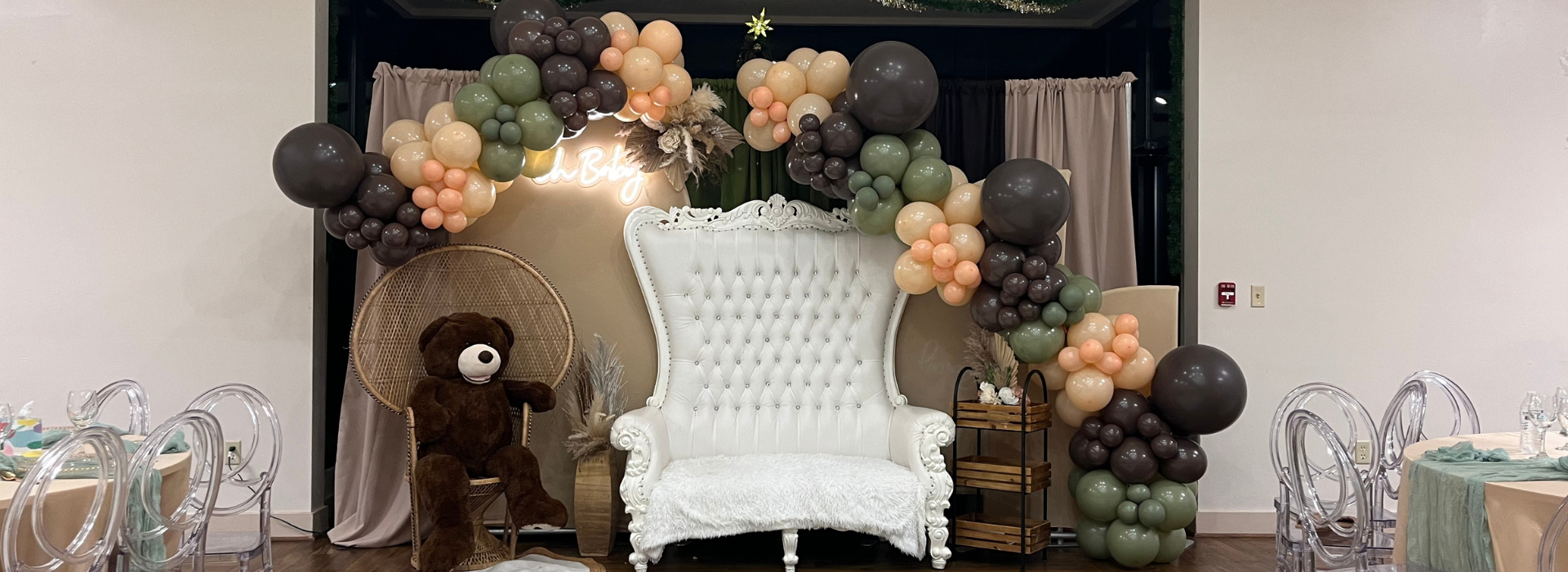 baby shower decor with a balloon arch and white chair