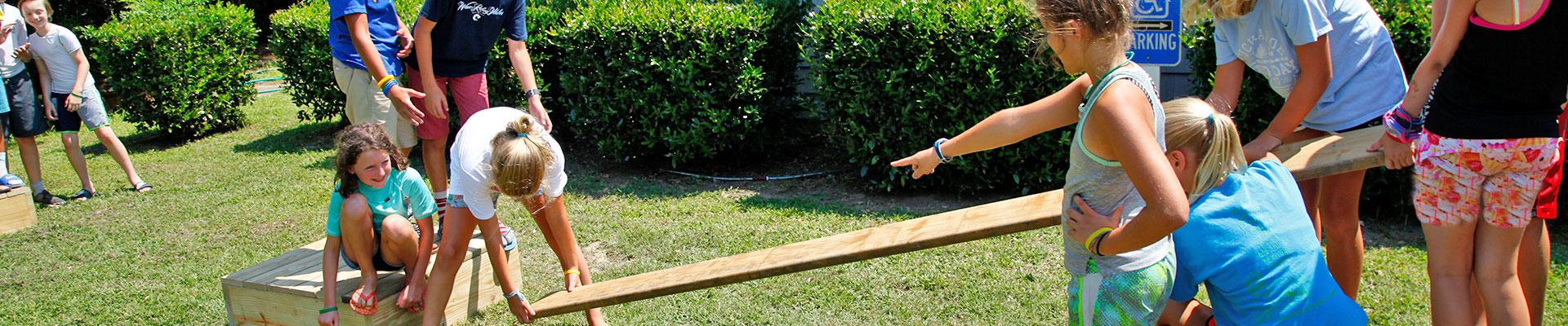 Campers lifting wood, working on team problem solving challenge at YMCA Camp Silver Beach