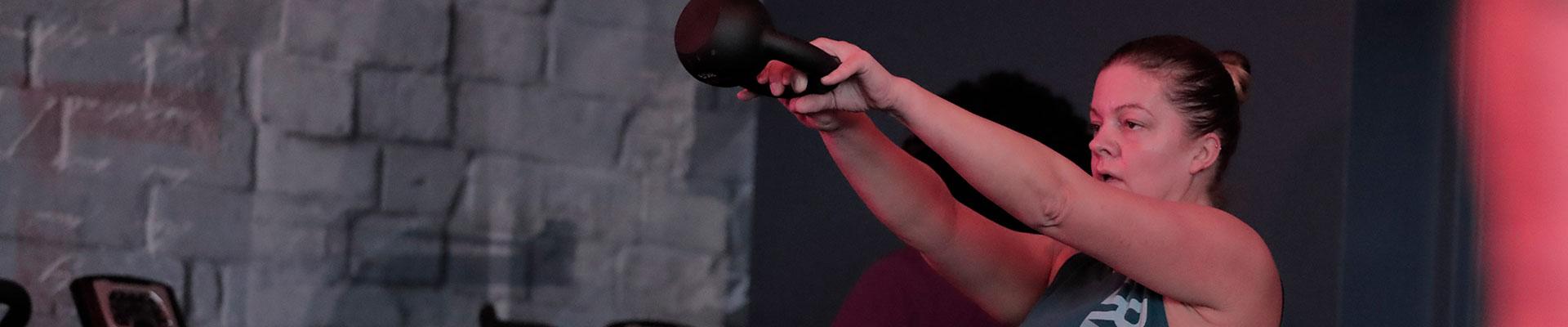 A woman swinging a kettlebell in the REGYMEN Fitness studio