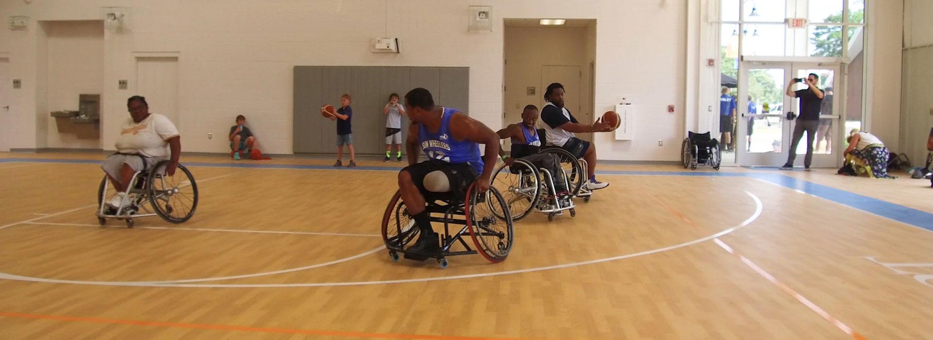 Men in wheelchairs playing basketball at YMCA JT's Camp Grom